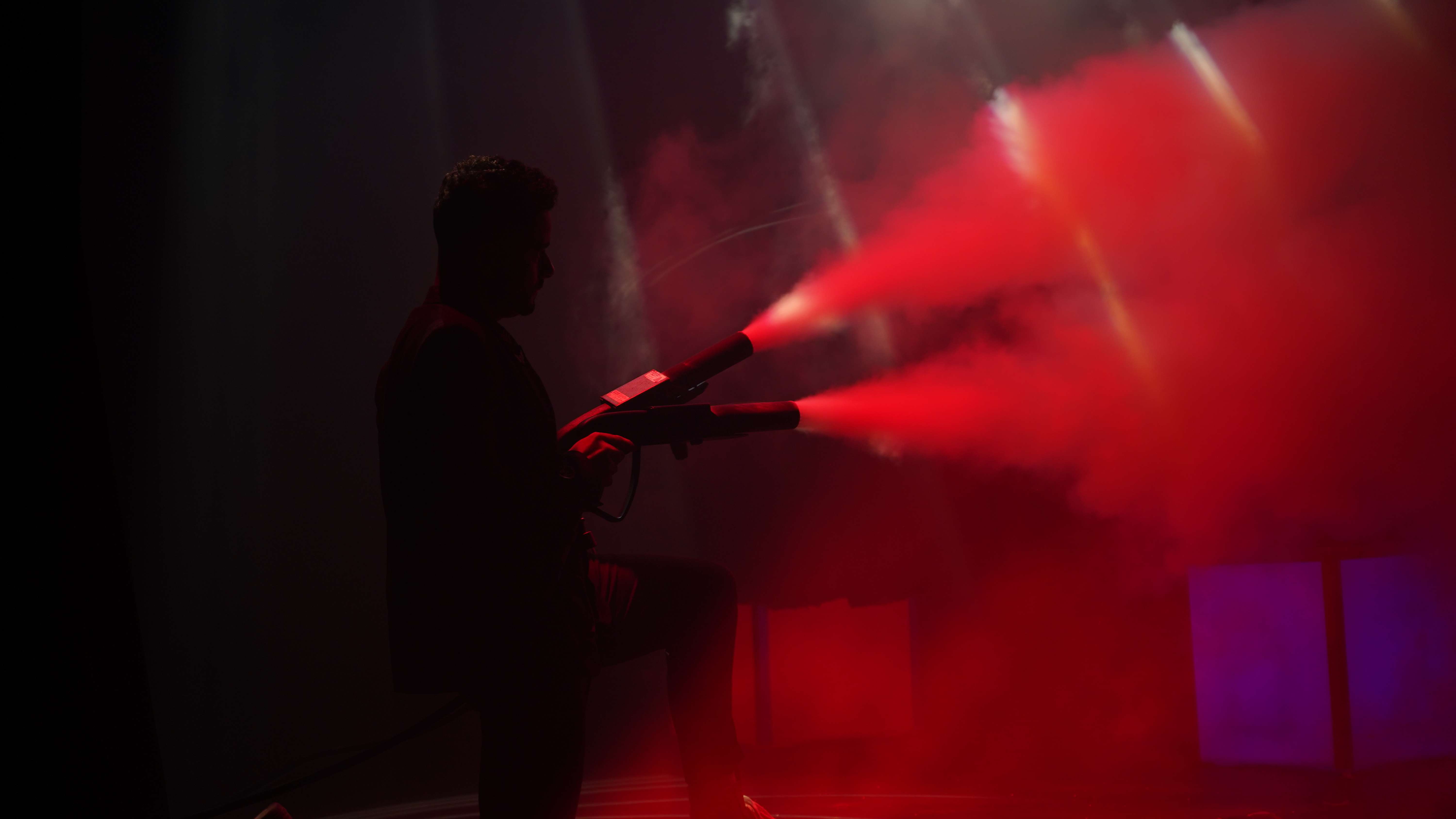 Silueta de un mago de Magicbros disparando un cañón entre haces de luz roja