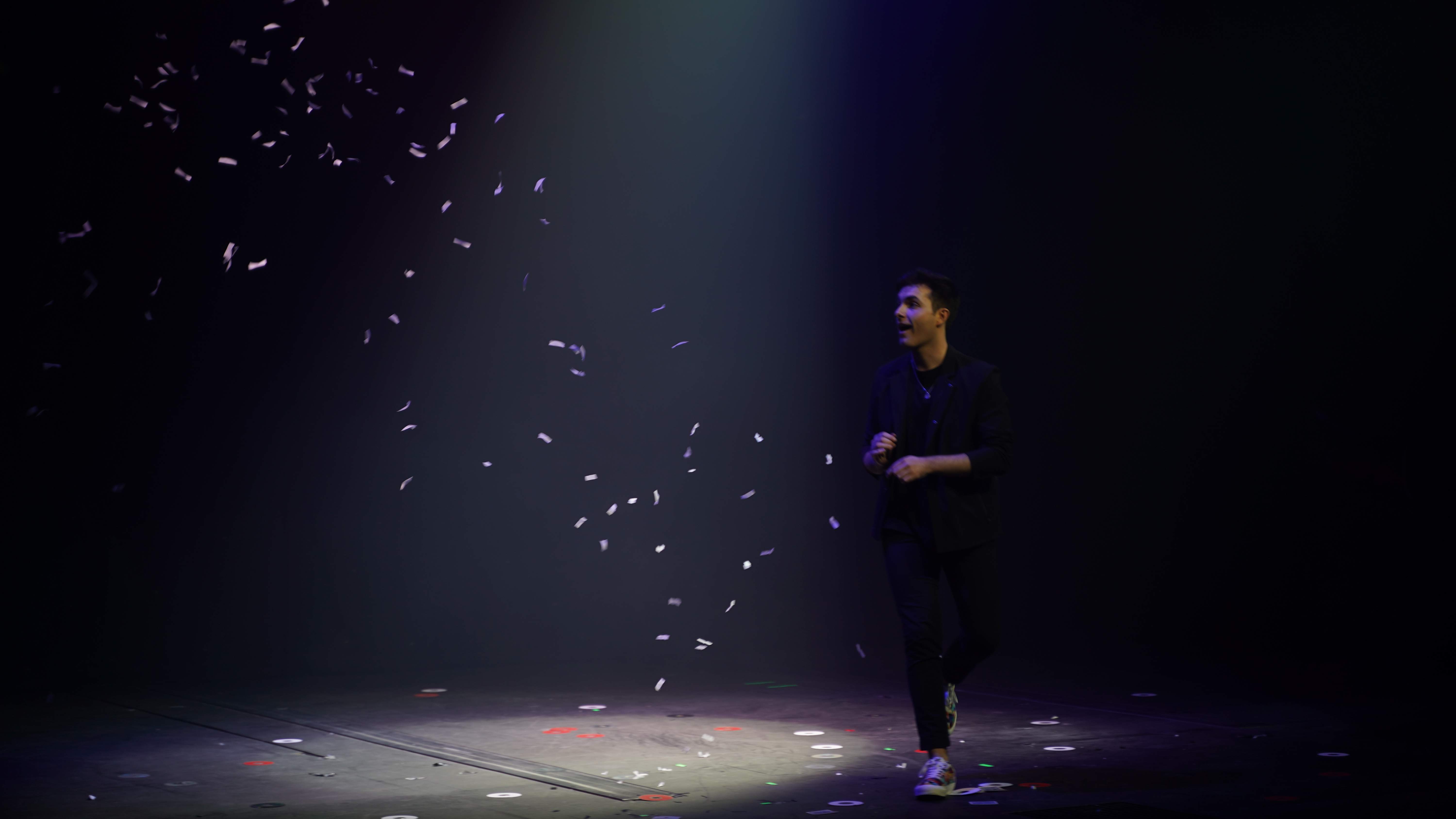Mago de Magicbros en el escenario con confeti cayendo bajo luz turquesa